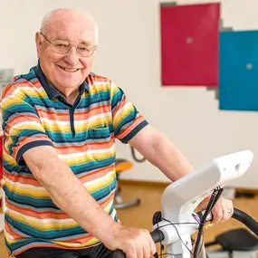 Senior beim Training auf dem Ergometer im Fitnessraum der Reha-Klinik