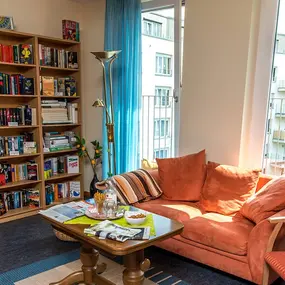 Gemütliche Leseecke mit Bücherregal, Sofa und Balkonfenster im Wohnzimmer