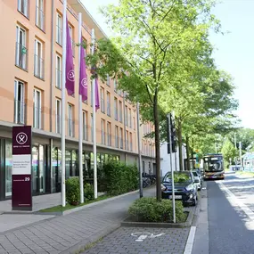 Eingang Pflegeheim in Dortmund mit lila Fahnen, Straße mit Bus und Bahn
